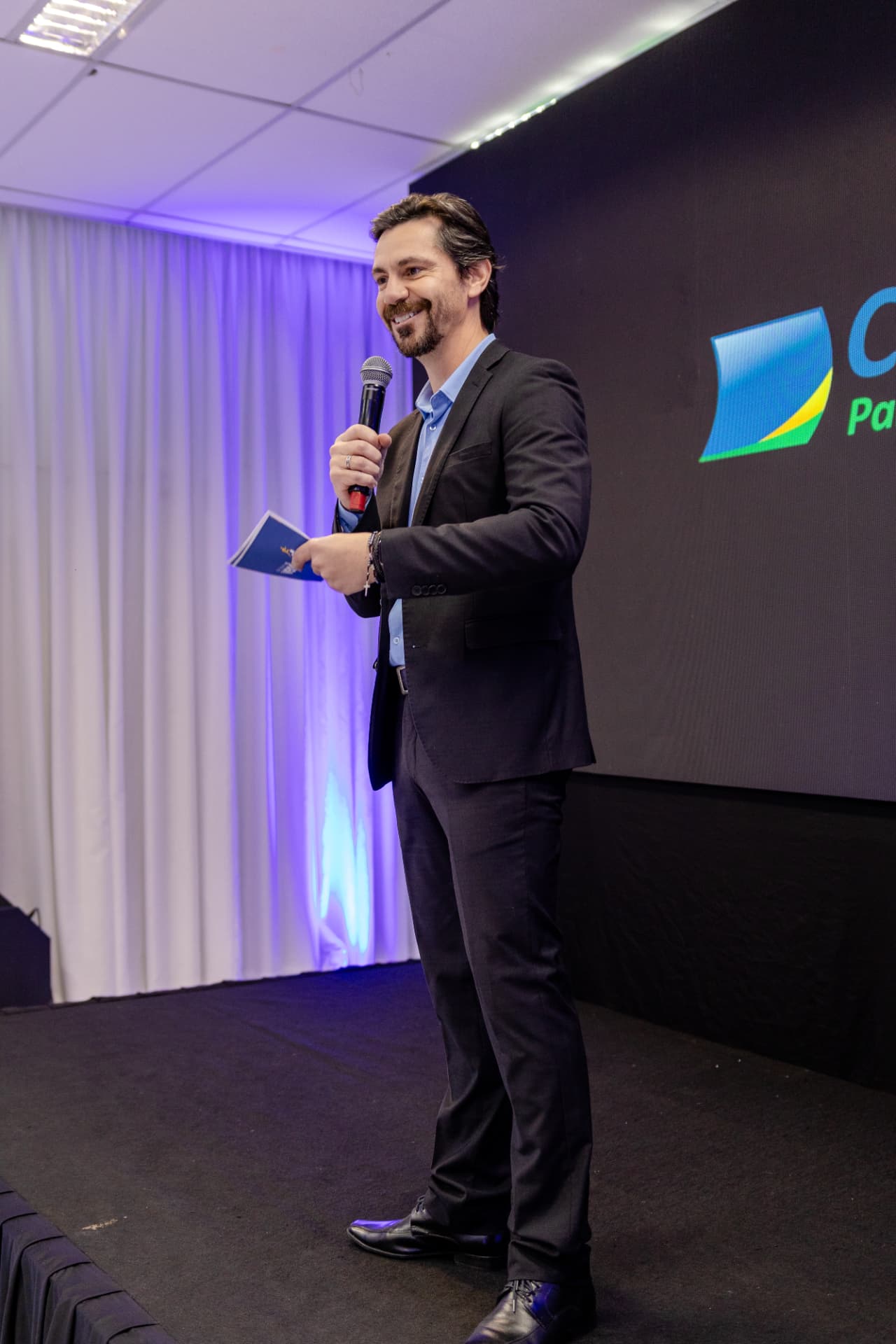 Ricardo Scappini sorrindo no palco durante o Seminário Vencer
