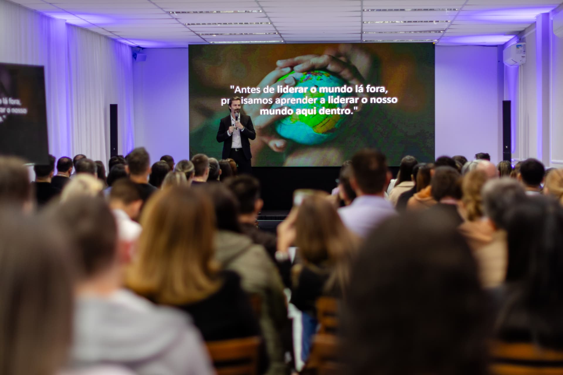 Visão ampla do palco e do público durante palestra de Ricardo Scappini